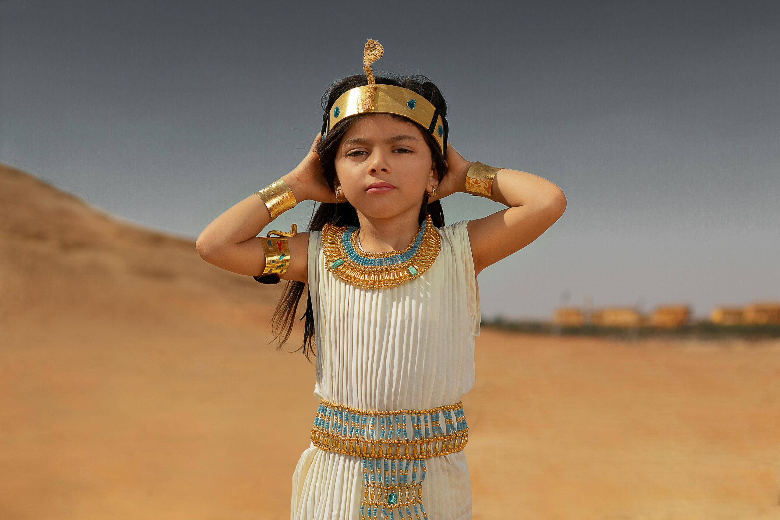 A little girl in an egyptian costume standing in the desert